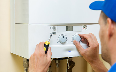 Heating engineer adjusting boiler controls in a residential setting.