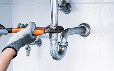 Repairing plumbing pipes with a wrench in a bathroom setting.